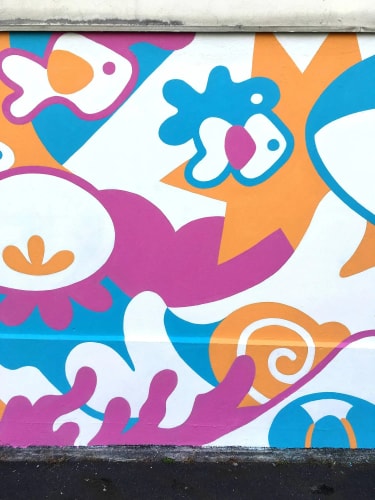 Peinture murale aux formes abstraites et colorées : poissons stylisés, motifs végétaux, courbes roses, oranges et bleues sur fond blanc, évoquant un monde sous-marin ludique.