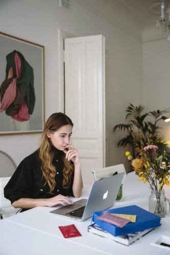 Femme assise à une table blanche travaillant sur un ordinateur portable MacBook.