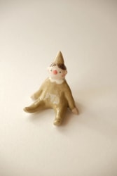 Trois bougies en céramique colorée disposées en triangle, ornées de médaillons gravés représentant une maison étoilée, un oiseau avec des fleurs et un motif botanique. Fond en bois clair.