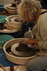 Une participante travaille la terre au tour dans l’atelier