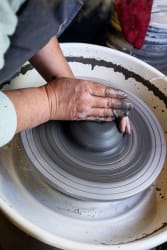 Mains guidant une pièce de terre sur le tour de potier