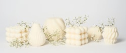 Bougies blanches de la marque Flamme de différentes formes décorées avec des petites fleurs blanches sur fond clair.