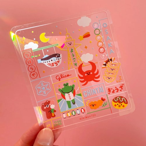 Un suncatcher sticker d'une illustration colorée représentant un parc avec un pédalo en forme de canard, une grenouille et un cochon dedans, des fleurs souriantes devant et des arbres derrière sur un fond vert.