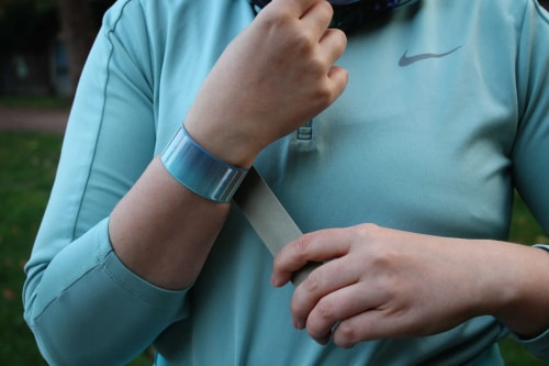 Un homme vêtu de vêtements de sport fait des étirements des jambes et porte un réflecteur au poignet pour l'aider à être vu dans l'obscurité.