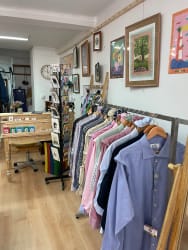 Portants de vêtements variés, avec chemises, vestes, robes et pantalons colorés, soigneusement suspendus dans une boutique.