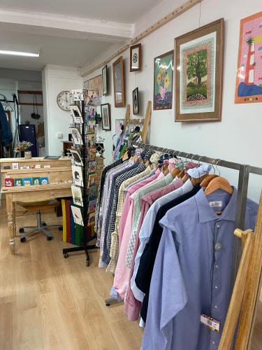 Portants de vêtements variés, avec chemises, vestes, robes et pantalons colorés, soigneusement suspendus dans une boutique.