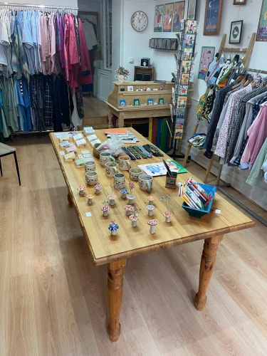 Portants de vêtements variés, avec chemises, vestes, robes et pantalons colorés, soigneusement suspendus dans une boutique.
