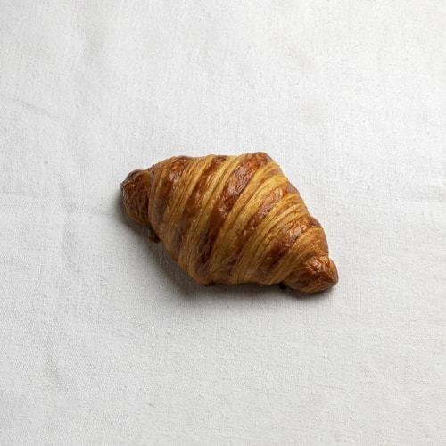 Un croissant doré posé sur une surface blanche