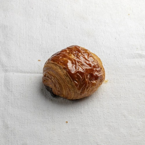 Petit pain au chocolat doré posé sur une nappe blanche