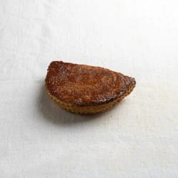 Une pâtisserie brune en forme de demi-lune posée sur un tissu blanc.