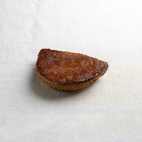 Une pâtisserie brune en forme de demi-lune posée sur un tissu blanc.