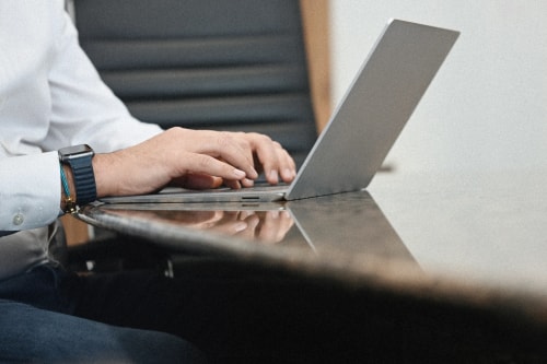 Un homme tapant sur un ordinateur portable sur une table en marbre, pour représenter l'accompagnement par Keystone Recrutement.